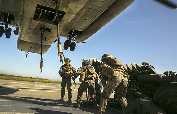 A Marine uses a static discharge wand to discharge excess static electricity before attaching an M777 howitzer to a CH-5