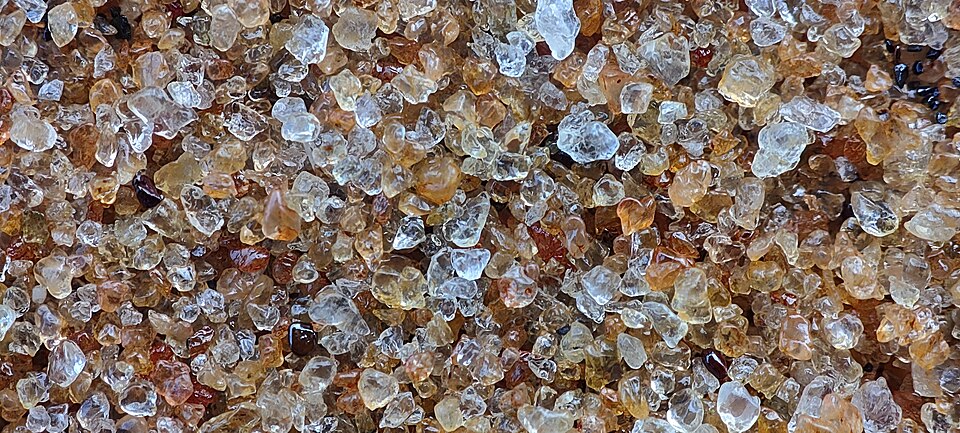 a close-up of beach sand: clear, tan and brown grains