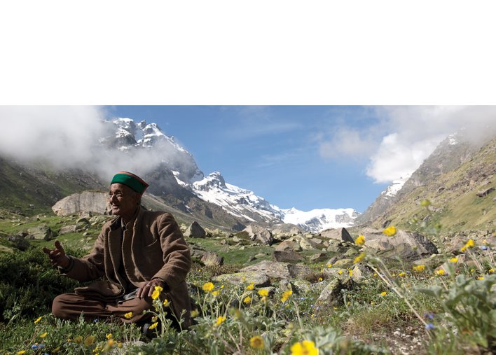 Happy old man seated under the mountains