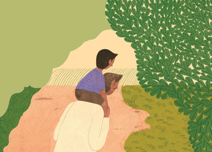 Boy sitting on his father's shoulders, on a path among trees