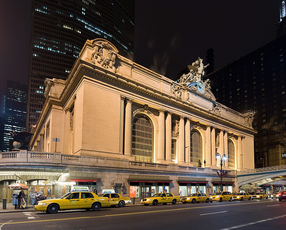 Grand Central Terminal, where New Yorkers board trains. The famous yellow New York taxis can be seen waiting on the street.